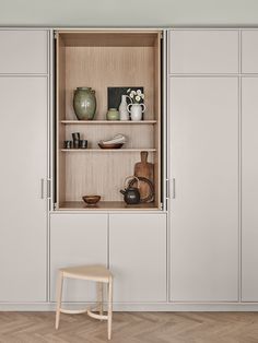 an open cabinet in the middle of a room with wooden flooring and white walls