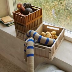 a window sill filled with stuffed animals next to a wooden crate on the windowsill