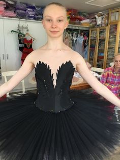 a woman in a black tutu with her arms stretched out