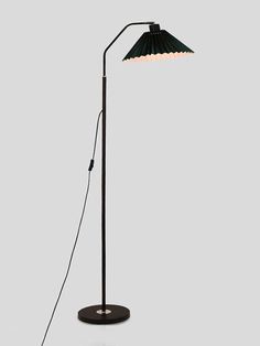 a black floor lamp with a white light on the base and a green shade over it