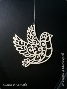 a white bird ornament hanging on a black leather surface with the word,'love