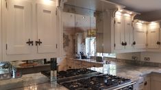 a kitchen with white cabinets and marble counter tops, along with a stove top oven