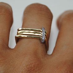 a close up of a person's hand wearing a gold ring with two diamonds