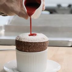 someone pouring sauce onto a cake on a plate