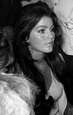 black and white photograph of woman sitting in front of other people at an event, looking off to the side