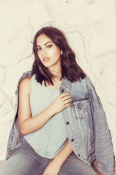 a woman sitting on the ground wearing a jean jacket