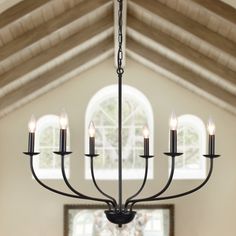 a chandelier hanging from the ceiling in a room with large windows and arched doorways