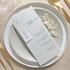 a table setting with place cards and gold cutlery on the plate, along with utensils