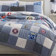 a bed with a blue and white patchwork comforter set on top of it