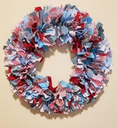 a red, white and blue wreath made out of old newspaper strips is hanging on the wall