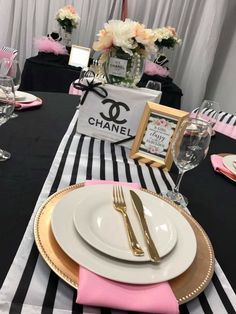 a black and white striped table cloth with pink napkins, gold rimmed plates and silverware