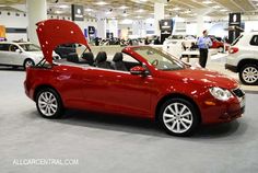 a red convertible car is on display at an auto show