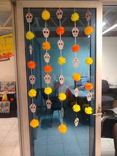 an open door decorated with yellow and orange paper pom - poms, hanging from it's sides