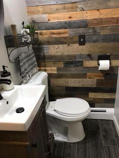 a white toilet sitting in a bathroom next to a sink and wooden planks on the wall