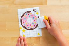 someone is cutting out a donut on a piece of paper with a sharpie