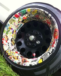 the tire is covered in comic stickers and has been painted with various colors on it