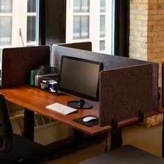 two computer screens sitting on top of a wooden desk in front of a large window