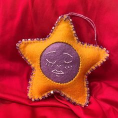 a yellow and purple star ornament sitting on top of a red cloth