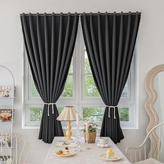 a dining room with white walls and black drapes on the windowsills, along with a table set for two