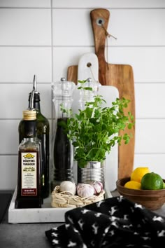 herbs, lemons, garlic and olive oil are sitting on a kitchen counter next to a cutting board