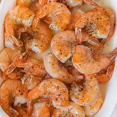 a white bowl filled with cooked shrimp on top of a wooden table