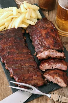 barbecue ribs and french fries on a slate platter next to a glass of beer