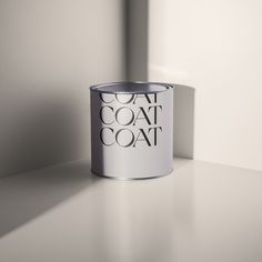 a white paint can sitting on top of a table next to a shadow from the wall