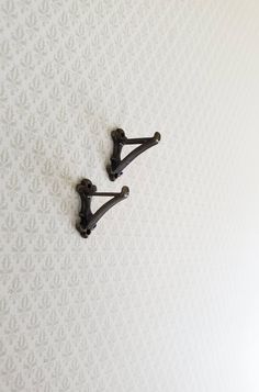 two black handles on the back of a white wallpapered room with floral designs