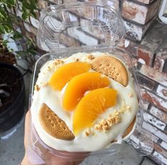 a person holding up a cake with oranges on it