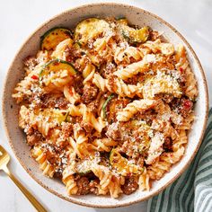 a bowl filled with pasta and meat next to a fork