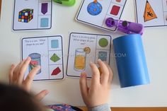 a child is playing with matching cards on the table in front of them, which include shapes and numbers