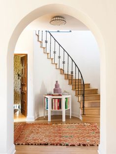 an archway leading to a staircase with books on the table and rug in front of it