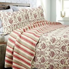 a bed with red and white bedspread next to a window