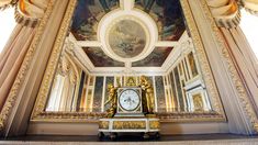 a clock is sitting in the middle of a room with paintings on the walls and ceiling