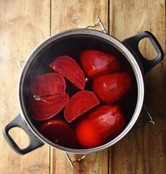 a pot filled with red onions on top of a wooden table