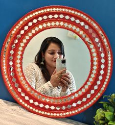 a woman looking at her cell phone in front of a round mirror with geometric designs on it