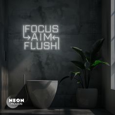 there is a neon sign that says focus aim flush on the wall next to a toilet