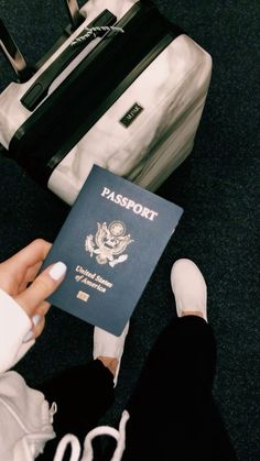 a person is holding a passport in front of a suitcase and another piece of luggage