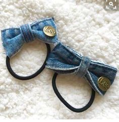 two denim hair ties on top of a white rug with gold buttons and black bows