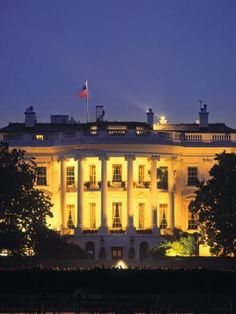 the white house lit up at night with lights on it's windows and trees