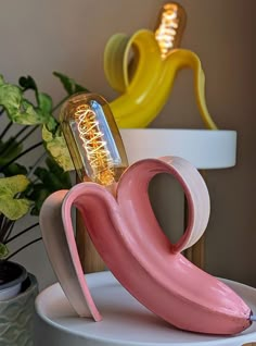 a pink flamingo light sitting on top of a table next to a potted plant