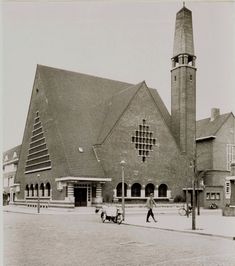 an old black and white photo of people walking in front of a building with a clock tower