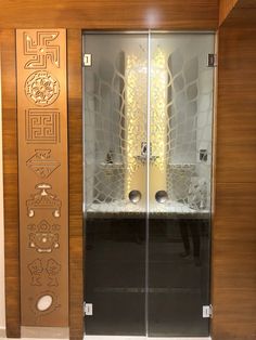 an open glass door with decorative designs on the outside and inside, in front of a wooden wall