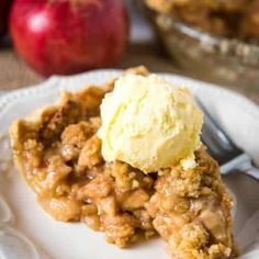 a piece of pie on a plate with ice cream and an apple in the background