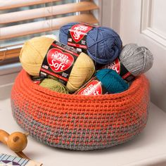 a basket filled with balls of yarn sitting on top of a table next to a book