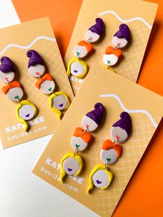 three brooches with different designs on them sitting next to each other in front of an orange background