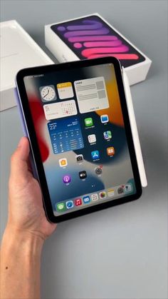 someone holding an ipad in their hand next to two boxes with the same product on them