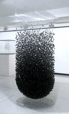 a large black sculpture sitting in the middle of a white floor covered with lots of dots