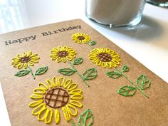 a birthday card with sunflowers on it and a glass of milk in the background