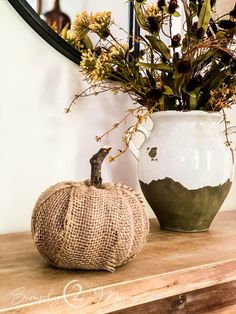 a vase filled with flowers sitting on top of a wooden table next to a mirror